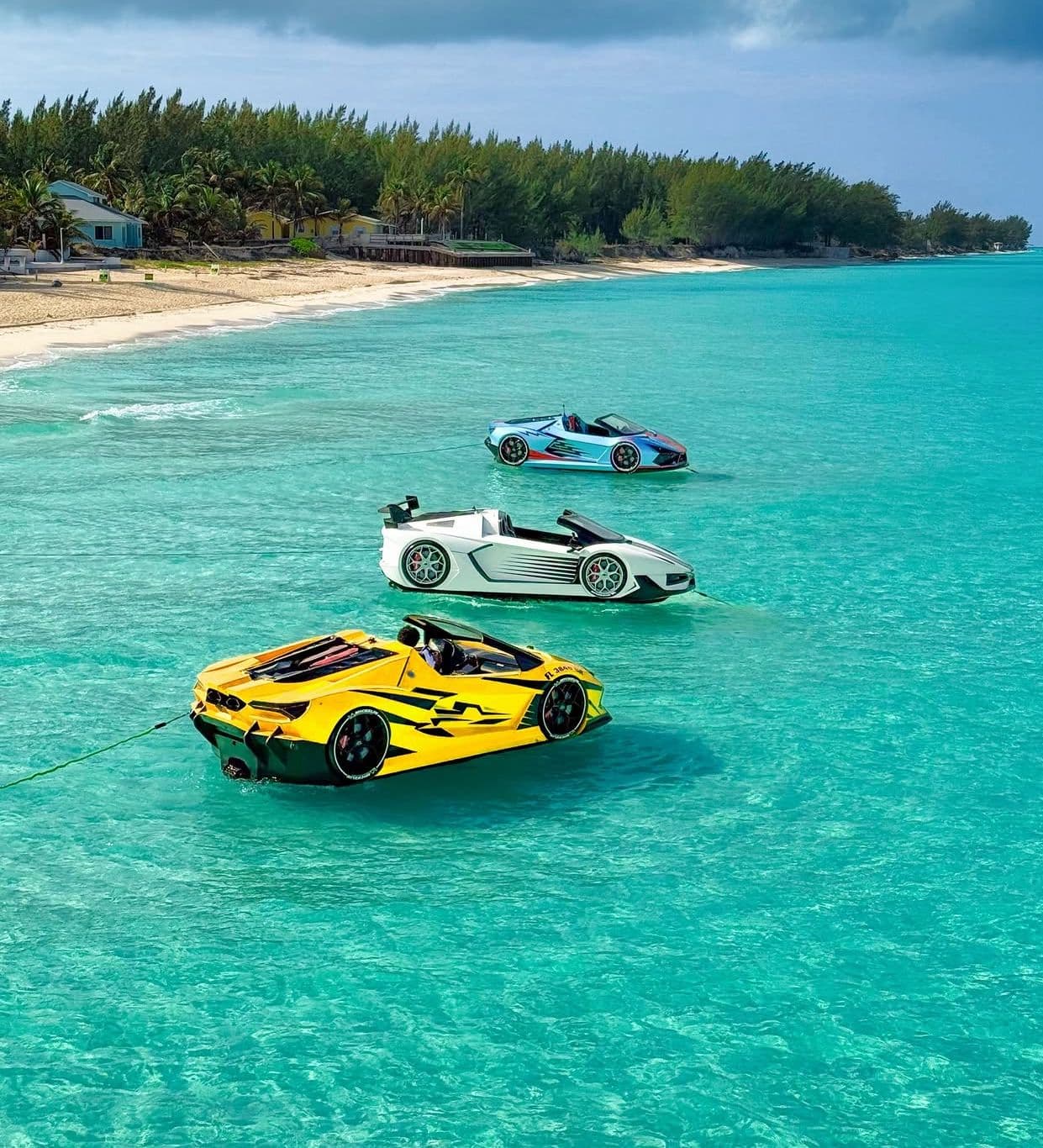Three colorful jet cars floating on clear turquoise water beside a beach